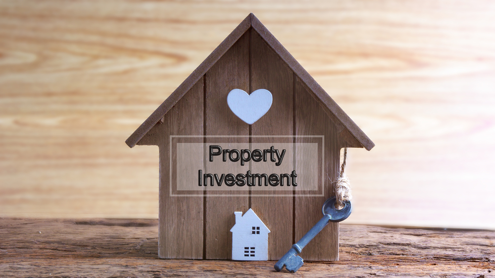 Conceptual image of miniature home icon made from wood and word written PROPERTY INVESTMENT on wooden base.Selective focus.
